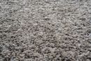 Nahaufnahme eines beigen Hochflor-Teppichs mit weicher, flauschiger Struktur und detailreicher Textur.