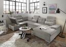 Modernes Wohnzimmer mit grauer Ecksofa, Couchtisch, Teppich, Wanddeko und großen Fenstern im Loft-Stil.