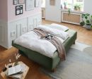 Modernes Schlafzimmer mit grünem Bett, Frühstückstablett, heller Bettwäsche und stilvoller Wanddekoration.