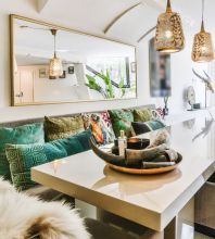 Modern eingerichteter Essbereich mit grossem Hochglanztisch, dekorativen Kissen und Hängelampen, oben links Text „Möbel Rieger Wohnstyling“.  