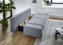 Graues Schlafsofa mit Holzfüßen, ausgeklappt und mit offenem Bettkasten, in modernem, hellen Wohnzimmer.