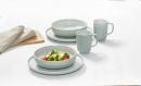 Modernes, helles Geschirr-Set mit Salat, Tassen und Tellern auf weißem Tisch, minimalistisches Design.