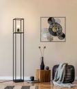 Moderne Stehlampe aus schwarzem Metall neben Holzhocker, Wanddeko und Wohnaccessoires im Wohnzimmer.