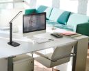 Moderne LED-Schreibtischlampe neben Computer auf weißem Bürotisch in hellem, stilvollem Büro mit Sofa.