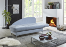 Modernes Wohnzimmer mit hellblauem Sofa, Kaminfeuer, großen Fenstern, Pflanzen und stilvollem Couchtisch.