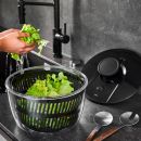 Frische grüne Salatblätter werden in einer Salatschleuder am modernen Küchenwaschbecken gewaschen.