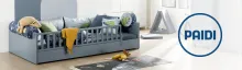 PAIDI Kinderzimmer mit Spielbett Modernes Kinderbett in Blau mit Kissen und Kuscheltieren; rechts PAIDI Logo und Spielzelt im Hintergrund.