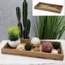 Rechteckiges Holztablett mit Deko-Kugeln, Kunstpflanze und Kaktus im Hintergrund auf weißem Tisch.