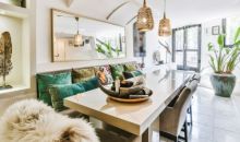 Modern eingerichteter Essbereich mit grossem Hochglanztisch, dekorativen Kissen und Hängelampen, oben links Text „Möbel Rieger Wohnstyling“.  