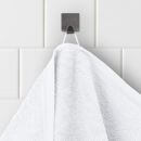 Weißes Handtuch hängt an Haken auf weiß gefliester Badezimmerwand, Nahaufnahme, Badezimmer-Accessoire.
