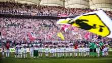 Fussballmannschaft des VFB Stuttgart steht Arm in Arm vor der Cannstatter Kurve im Stadion