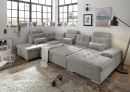 Modernes Wohnzimmer mit großer grauer Ecksofa-Landschaft, Teppich, Stehlampe und dekorativen Accessoires.