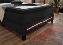 Modernes Boxspringbett mit dunklem Stoffbezug, LED-Beleuchtung und Holzboden im gemütlichen Schlafzimmer.