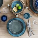 Tisch mit blau-grauem Keramikgeschirr, Gläsern, Besteck und Limetten auf Holz, modern gedeckt.