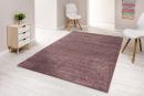 Moderner, rechteckiger Teppich in Rosa auf hellem Laminatboden in minimalistisch eingerichtetem Wohnzimmer.