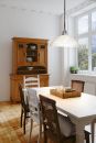 Heller Essbereich mit Holztisch, Stu00fchlen, Vitrine, grou00dfer Fensterfront und Blick ins Gru00fcne.