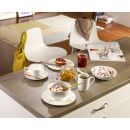 Frühstückstisch mit Müsli, Joghurt, Kaffee, Croissant, Marmelade und Cappuccino in modernem Esszimmer.