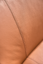 Nahaufnahme einer braunen Ledercouch mit feiner Narbung und sichtbarer Naht, hochwertiges Ledersofa-Detail.