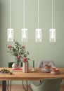 Moderner Essbereich mit Holztisch, Blumen, Geschirr und vier hängenden Designer-Lampen vor grüner Wand.