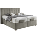 Modernes Boxspringbett in Grau mit hohem, gestepptem Kopfteil, zwei Matratzen und dekorativer Tagesdecke.