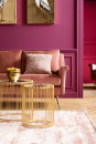 Modernes Wohnzimmer mit rosa Samtsofa, goldenen Beistelltischen und pink gestrichener Wand im eleganten Design.