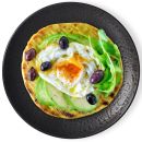 Fladenbrot mit Avocado, Spiegelei, Rucola und Oliven auf schwarzem Teller, gesundes Frühstück