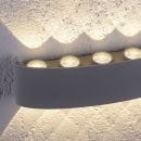 Moderne LED-Wandleuchte aus Metall, erzeugt dekoratives Lichtmuster an weißer Wand, energiesparend.
