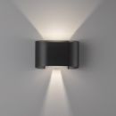 Moderne schwarze Wandleuchte aus Metall, strahlt warmes Licht nach oben und unten an eine weiße Wand.