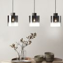 Drei moderne Pendelleuchten über Esstisch mit Keramikschalen, Gläsern und dekorativem Zweig, minimalistisches Design.