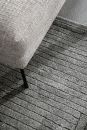 Webteppich SW Pure Design D.242 Anthrazit 200 x 290 cm Grauer Teppich mit Strukturmuster neben hellgrauem Sofa mit schwarzem Bein auf Betonboden, modernes Wohnzimmer.