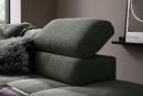 Modernes, grünes Sofa mit verstellbarer Kopfstütze und Kissen, vor beiger Wand und Bauhaus-Poster.
