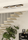 Moderne LED-Deckenleuchte mit Holz und Metall über offener Treppe in minimalistischem Wohnzimmer mit Pflanze.