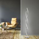 Moderne LED-Stehlampe in Spiralform im Wohnzimmer mit gelbem Sessel, Holzboden und grauer Wand.