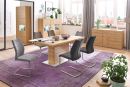 Modernes Esszimmer mit Holztisch, grauen Stühlen, lila Teppich, Pflanzen und viel Tageslicht.