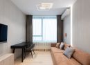 Modernes Wohnzimmer mit braunem Sofa, Schreibtisch, Stuhl, großem Fenster, Vorhängen und Klimaanlage.