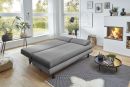 Modernes Wohnzimmer mit grauem Schlafsofa, Kamin, Holzboden, großen Fenstern und stilvoller Dekoration.