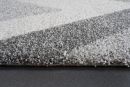 Nahaufnahme eines modernen, grauen und weißen Hochflor-Teppichs auf dunklem Boden, weiche Textur sichtbar.