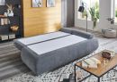 Graues Schlafsofa im modernen Wohnzimmer, ausgeklappt als Bett, mit Teppich, Couchtisch und Dekoration.