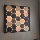 Beleuchtetes Wandbild mit sechseckigen, wabenförmigen LED-Elementen im modernen Design an weißer Wand.