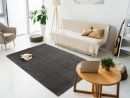 Modernes Wohnzimmer mit grauem Teppich, Sofa, Pflanzen, Gitarre, Laptop und viel Tageslicht.