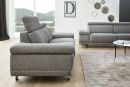 Modernes Wohnzimmer mit grauem Sofa, Teppich, Wanddeko und großem Fenster mit Ausblick auf grüne Hügel.