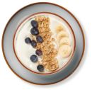 Joghurt-Bowl mit frischen Blaubeeren, Bananenscheiben und knusprigem Müsli auf einem Teller, Draufsicht.