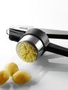 Kartoffelpresse aus Edelstahl presst gekochte Kartoffeln zu feinem Püree, Küchenutensil auf weißem Hintergrund.