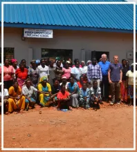 Gruppenfoto vor einem Gebäude mit Schild „Women Empowerment Tailoring School“, viele Frauen und einige Männer stehen zusammen.