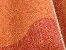 Nahaufnahme eines orange-roten Teppichs mit weicher, strukturierter Oberfläche und dichter Florstruktur.