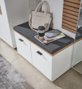 Weiße Sitzbank mit grauem Polster, Tasche, Kaffeebecher und Zeitschriften im modernen Flur auf Holzfußboden.