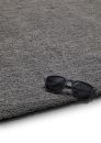 Schwarze Sonnenbrille liegt auf grauem Teppichboden, modernes Wohnaccessoire, minimalistisches Design.