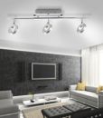 Moderne LED-Deckenleuchte mit drei Spots im stilvollen Wohnzimmer mit grauer Couch und Wand-TV.
