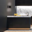 Moderne schwarze Küche mit Marmorarbeitsplatte, goldenen Zitronen und stilvoller LED-Beleuchtung.