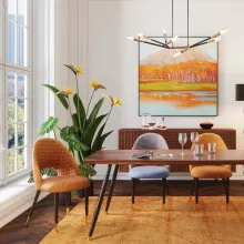 Ein stilvoll eingerichtetes Esszimmer mit dem KARE Stuhl "Hudson" in Orange, der über eine strukturierte Polsterung und schwarze Metallbeine mit goldfarbenen Akzenten